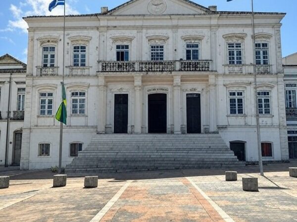 Edifício governamental em Natal, RN, com bandeiras do Brasil e do estado, representando eleições e apoio político.