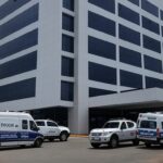 Hospital em Taguatinga com viaturas policiais, representando prisão de técnicos de enfermagem por injetar desinfetante em pacientes de UTI.