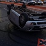 Carro capotado em rodovia de Brasília, viatura policial ao fundo, acidente com motorista alcoolizado no DF.