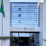 Fachada da sede da Polícia Federal em Brasília com avião no céu, simbolizando determinação ignorada e permanência nos EUA.