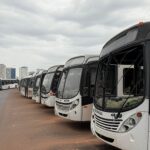 Ônibus depredados por vândalos em rua de Brasília, DF, com danos visíveis em vidros e carrocerias.