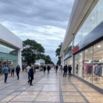 Avenida comercial em Brasília com lojas e vitrines, ilustrando crescimento de 5,7% no varejo limitado por juros altos.