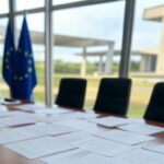 Mesa de conferência em Brasília com bandeiras da UE e Mercosul, representando acordo histórico de livre-comércio.