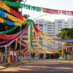 Rua na Asa Norte de Brasília com decorações de carnaval do Bloco Vai Quem Fica, ambiente festivo familiar.