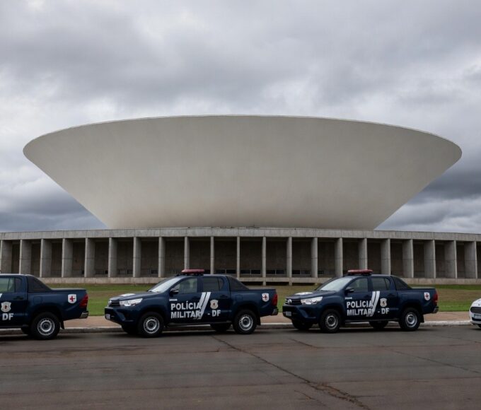 Viatura da polícia da CLDF em frente à Câmara Legislativa no DF, com elementos de olimpíadas de segurança e tom de controvérsia.