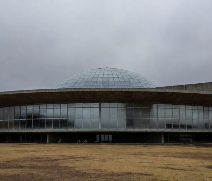 Edifício da CLDF em Brasília com bandeiras e pedestal simbólico de título honorário, em meio a críticas por desvio de foco.
