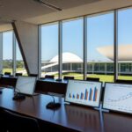 Sala de conferências em Brasília com vista para o Congresso, representando debates sobre desafios na implementação do ECA Digital.