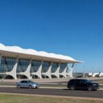 Vista do Aeroporto de Brasília com terminal moderno e aviões no pátio, ilustrando priorização de leilão governamental.