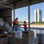 Caixas de vacinas contra Covid-19 chegando ao Distrito Federal do Ministério da Saúde, em estilo fotojornalístico.