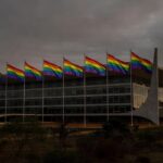Fachada da CLDF em Brasília com bandeiras do Orgulho LGBTI+ sob luz dramática
