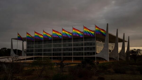 Fachada da CLDF em Brasília com bandeiras do Orgulho LGBTI+ sob luz dramática