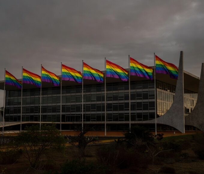 Fachada da CLDF em Brasília com bandeiras do Orgulho LGBTI+ sob luz dramática