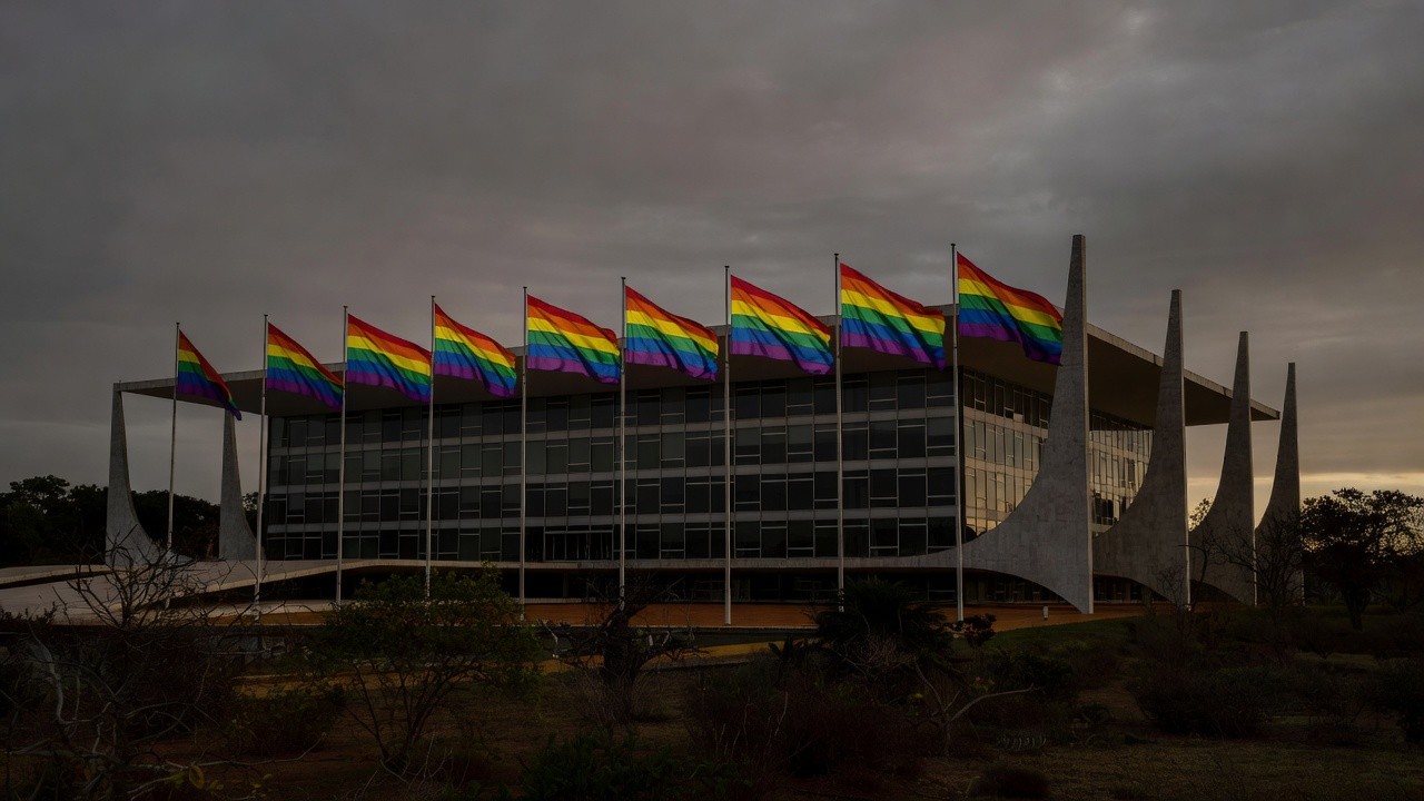 Fachada da CLDF em Brasília com bandeiras do Orgulho LGBTI+ sob luz dramática